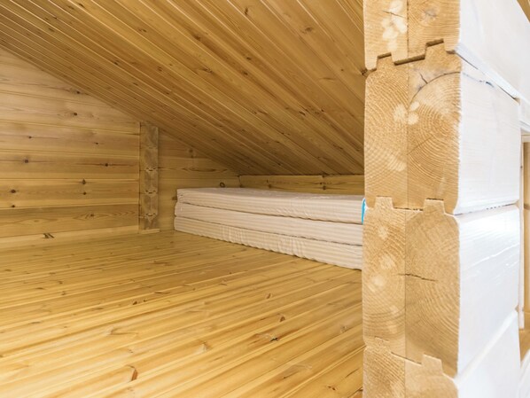 Een houten zolderkamer met een schuine plafond en een matras op de vloer.