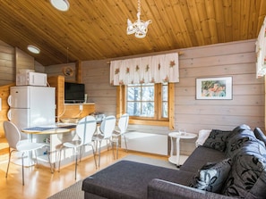 Een gezellig chalet interieur met een eethoek, een bank en een televisie.