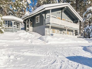 A two-story building with a balcony and a covered entrance, surrounded by snow.