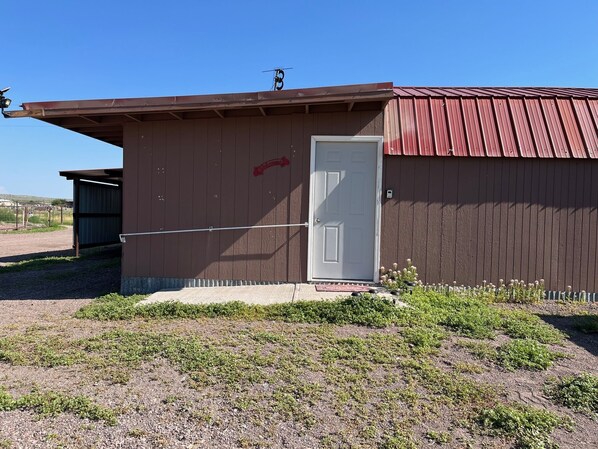 A small, single-story building with a red roof and a white door.