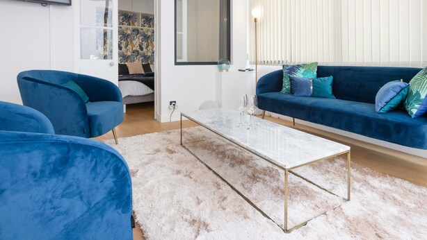 A modern living room with a blue sofa, a matching blue armchair, and a white coffee table. - Modern 2-Br Apartment in the Heart of Cannes (Cannes)