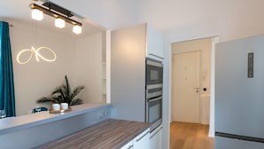 A modern kitchen with a wooden countertop, built-in oven, and a large mirror with integrated lighting. - Modern 2-Br Apartment in the Heart of Cannes (Cannes)
