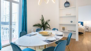 A modern dining area with a round table, blue chairs, and a decorative light fixture. - Modern 2-Br Apartment in the Heart of Cannes (Cannes)