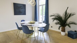 A dining area with a round table, blue chairs, a potted plant, and a modern light fixture. - Modern 2-Br Apartment in the Heart of Cannes (Cannes)
