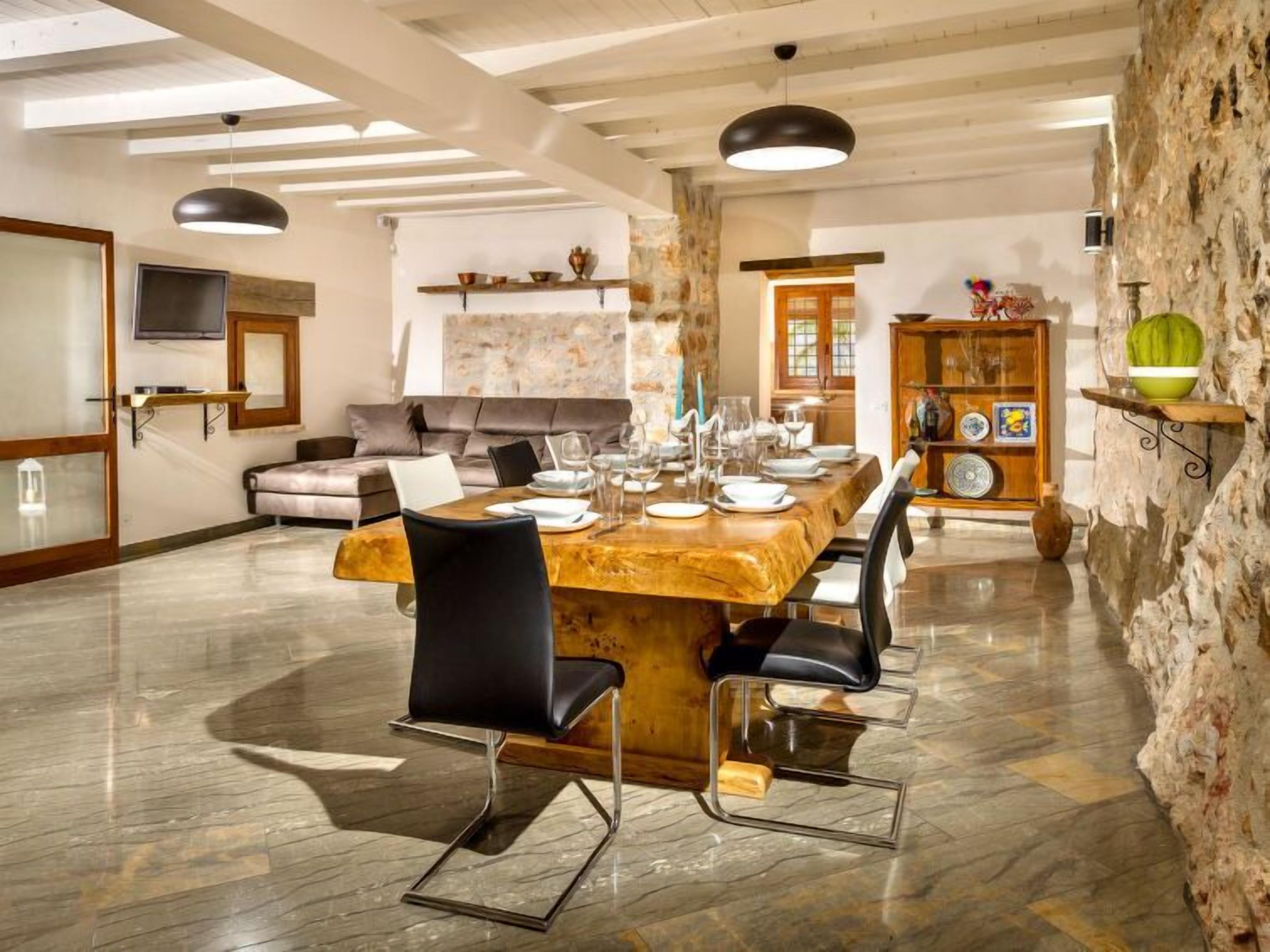 A spacious dining area with a long wooden table set for six, surrounded by modern chairs.
