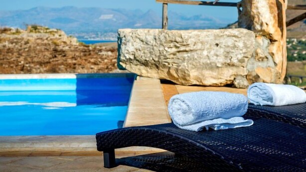 A poolside area with a lounge chair and a towel, overlooking a clear blue pool and a mountainous landscape. - Le Muse by Interhome (Castellammare del Golfo)