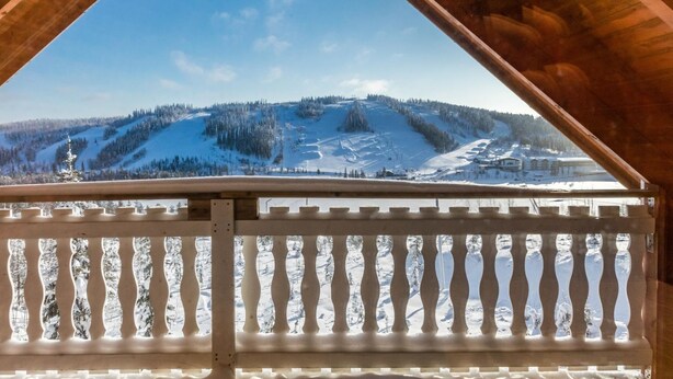 A wooden balcony with a view of a snow-covered mountain landscape.
