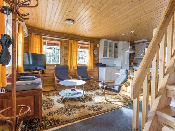 A cozy cabin interior with a TV, seating area, and kitchen.