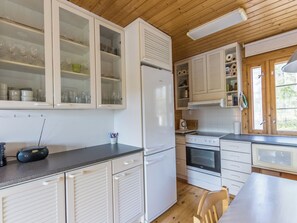Una cocina con armarios blancos, un refrigerador, un horno y un microondas.