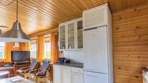 A wooden cabin interior with a dining area, kitchen, and a television.