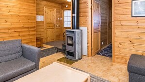 A wooden interior with a fireplace, two grey sofas, and a wooden floor.