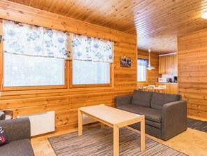 Een houten blokhutinterieur met een bank, tafel en een keukenhoek.