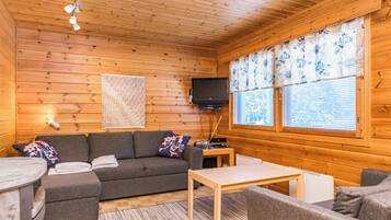 L’intérieur d’un chalet confortable, avec un canapé, une petite table et un téléviseur.