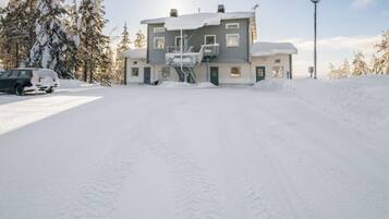 A two-story building with a covered staircase and a snow-covered driveway.