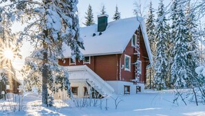 A snow-covered house with a red exterior, a visible staircase, and a chimney. - Kulma-alpit a by Interhome (Hyrynsalmi)
