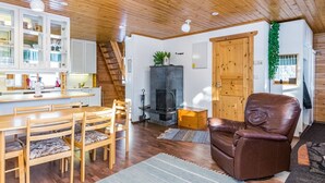 A cozy cabin interior with a wooden dining table, chairs, a fireplace, and a comfortable leather armchair. - Kulma-alpit a by Interhome (Hyrynsalmi)