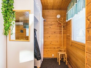 A compact room with a wooden interior, a small stool, a coat rack, and a mirror on the wall. - Kulma-alpit a by Interhome (Hyrynsalmi)