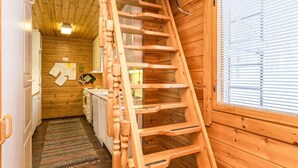 A wooden interior with a wooden staircase, a kitchen area, and a window with blinds. - Kulma-alpit a by Interhome (Hyrynsalmi)