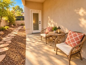 A patio area with a wicker chair and table, a potted plant, and a lantern.
