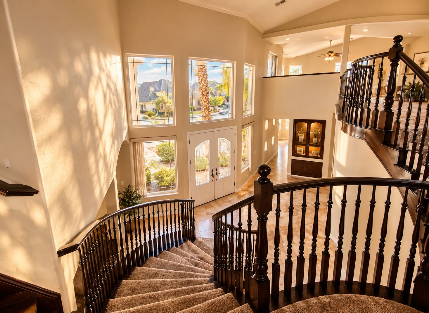 Interior com vários níveis, uma escadaria imponente, grandes janelas e vista para o exterior.