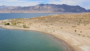 A desert landscape with a large body of water and distant mountains.