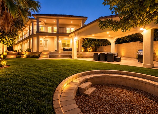 A two-story house with a covered patio, outdoor seating, and a fire pit.