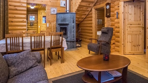 A log cabin interior with a fireplace, wooden furniture, and a cozy seating area.