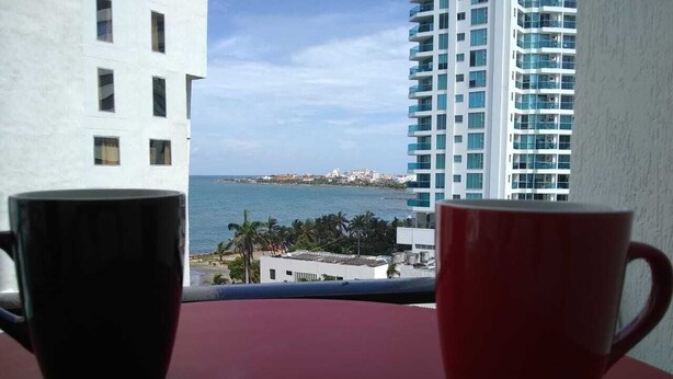 Duas canecas sobre uma mesa com vista para a paisagem urbana costeira.