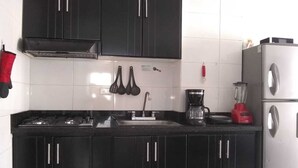 Uma cozinha com armários pretos, uma geladeira de aço inoxidável, uma pia e um fogão.