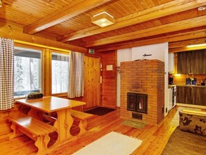 Cozy cabin-style room with a dining table, fireplace, and kitchen area, perfect for a peaceful retreat in nature.
