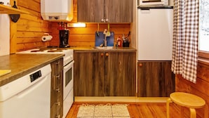 Een compacte keuken met houten kastjes, een ingebouwde magnetron, een koffiezetapparaat en een spoelbak.