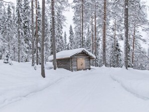 Cozy cabin nestled among snow-laden trees, offering a secluded retreat.