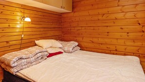 Een kamer met houten lambrisering, een bed, een wandlamp en een plafondlamp.