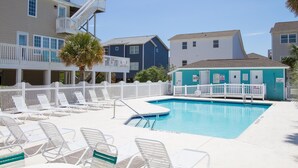 A swimming pool area with lounge chairs and a poolside building. - 4BR beach getaway steps away from the beach with community pool (Ocean Isle Beach)