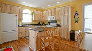A kitchen with wooden cabinets, a central island, a microwave, and a stove. - 4BR beach getaway steps away from the beach with community pool (Ocean Isle Beach)