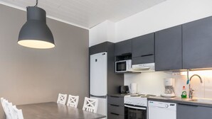 A modern kitchen with a dining table and chairs, a refrigerator, microwave, coffee maker, and dishwasher.
