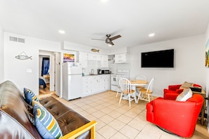 Cozy living space with a kitchenette, dining area, and seating arrangements, featuring a flat-screen TV and comfortable furniture.