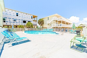 Relax by the clear blue pool surrounded by lounge chairs and a shaded patio area.