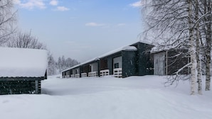 A snow-covered building with multiple rooms, a covered outdoor area, and a snow-covered landscape.