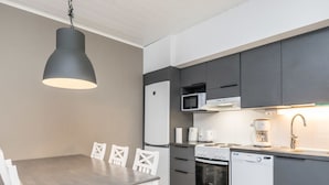 A modern kitchen with a dining table, chairs, a refrigerator, microwave, stove, and dishwasher.