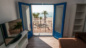 Una habitación con vista a la playa, un televisor sobre un soporte y una cama.