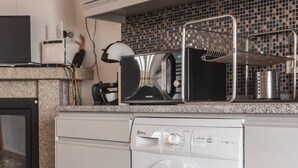 A modern kitchen with a built-in washer and dryer, a microwave, and a tiled backsplash. - Casa d’El Rey, Serra da Freita/Passadiços do Paiva (Mizarela)