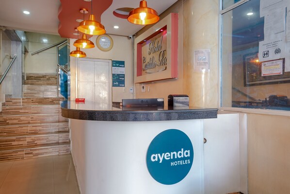 A hotel reception area with a modern design, including a reception desk, a clock, and a staircase leading to other floors. - Hotel Ayenda Castillo Real 1521 (Bucaramanga)