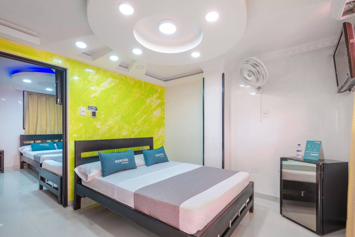 A modern hotel room with a bed, bedside table, and a small desk with a chair.
