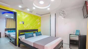 Una habitación de hotel moderna con cama, mesita de noche y un pequeño escritorio con silla.