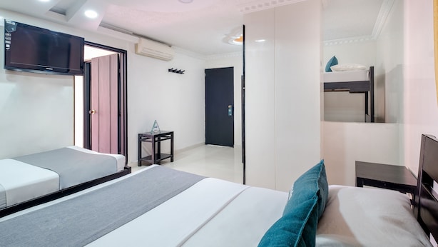Een moderne hotelkamer met een groot bed, een tv aan de muur, een klein tafeltje en een kledingkast.