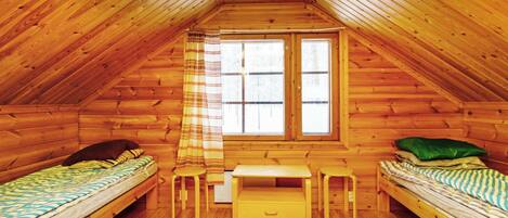 Una pequeña cabaña de madera con dos camas, una ventana y un banco.