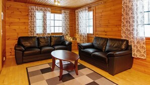 A cozy cabin with two leather sofas, a small wooden table, and patterned curtains.
