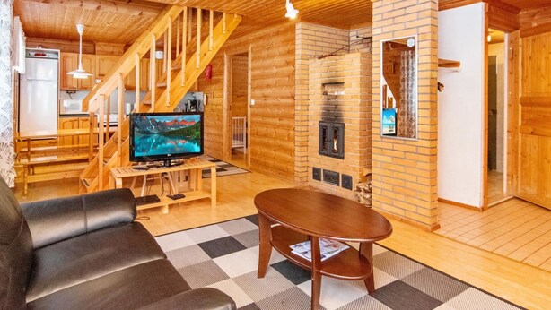A wooden interior with a TV, sofa, and fireplace.