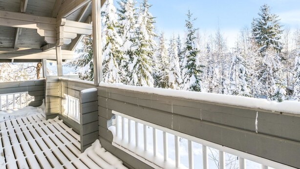 Ein Holzbalkon mit Blick auf schneebedeckte Bäume.